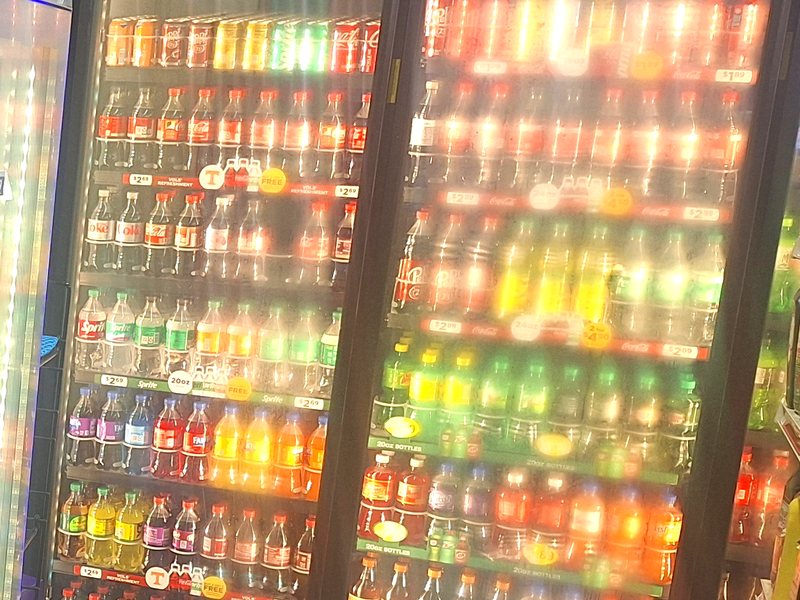 Cooler doors stocked with bottled sodas, juices, and water at Stop N Shop