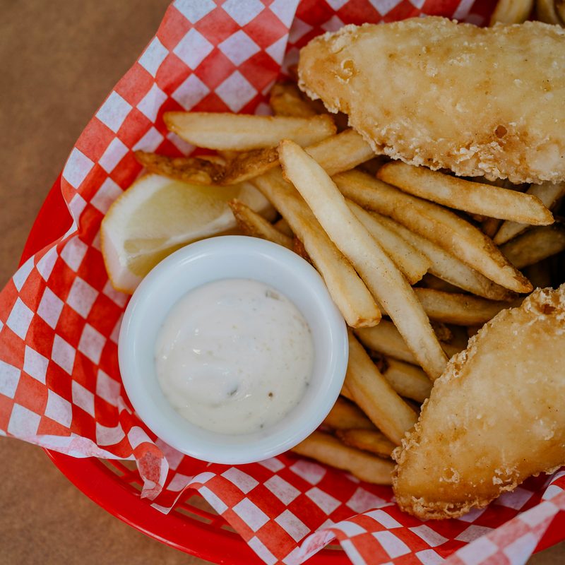 Fried fish fillets with fries in a basket